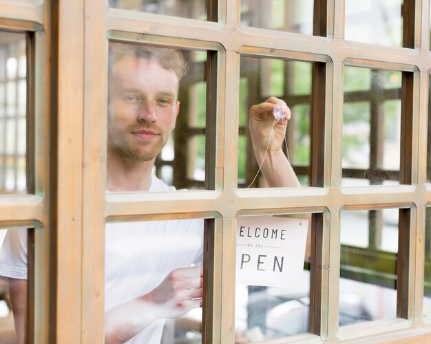 Man putting up open sign on coffee shop window
