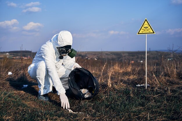 Мужчина в радиационном костюме собирает мусор на улице