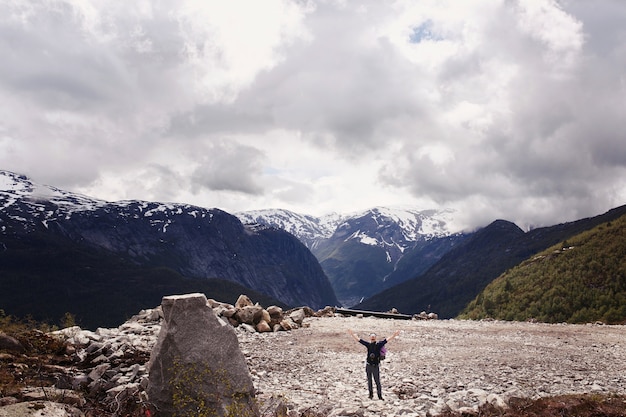 Man raises his hands up posing before gorgeous mountains in Norway