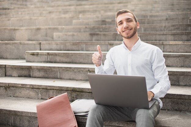 Man raising his big finger up while sitting on stairs