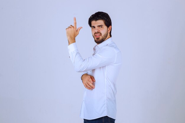 Man raising his hand up and pointing at something above.