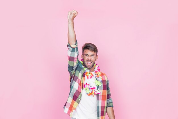 Человек, подняв руку в поддельной цветочной гирлянде на шее на розовом фоне