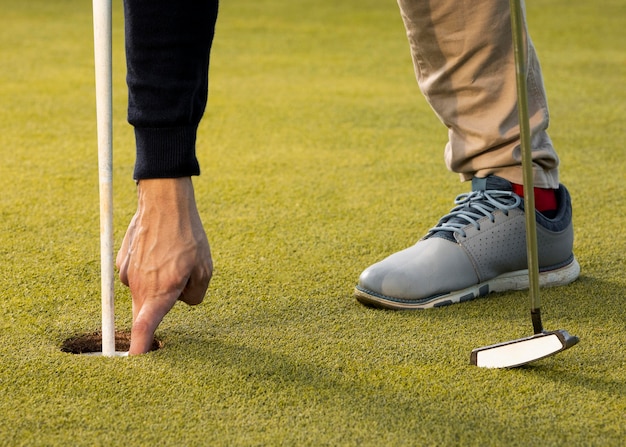 Free photo man reaching into golf ball hole with hand