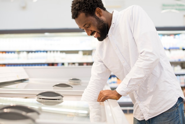 Free photo man reaching out into supermarket freezer