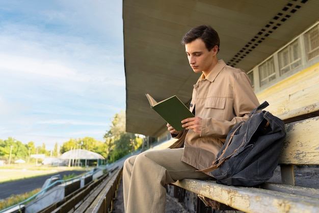 Man reading book outdoors side view