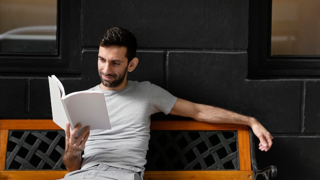 Foto gratuita uomo che legge un libro interessante su una panchina