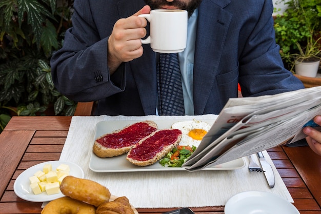 レストラン、新聞、コーヒーを飲んでいる男