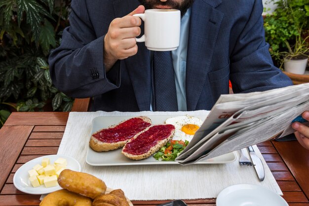 レストラン、新聞、コーヒーを飲んでいる男