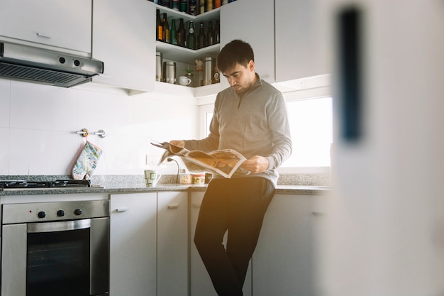 Мужчина читает газету на кухне