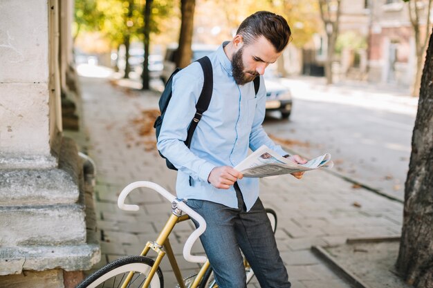 Man reading newspaper near bicycle