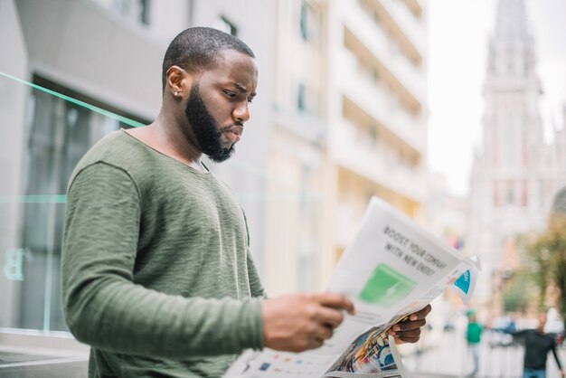 Man reading newspaper on street