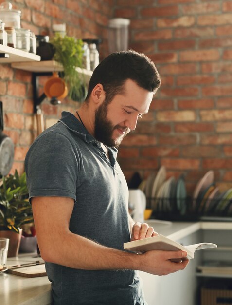 Man reading a recipe book in the kitchen