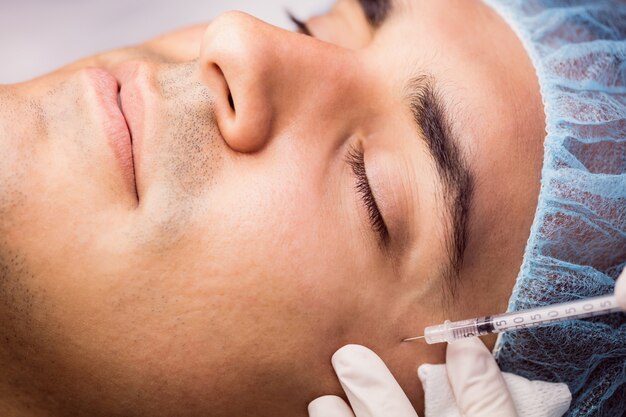 Man receiving botox injection on his face