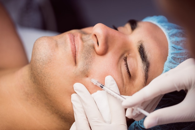Man receiving botox injection on his face