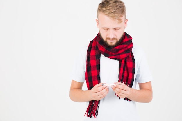 Человек в красном клетчатом шарфе с термометром