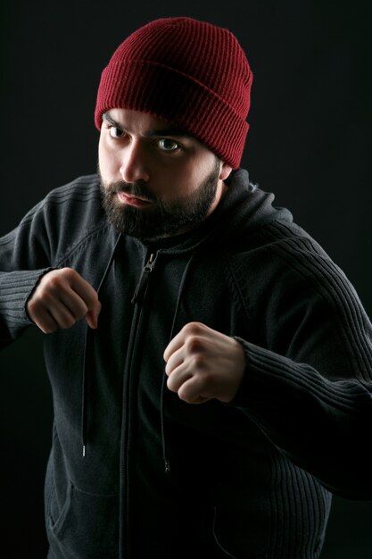빨간 모자와 회색 재킷을 입은 남자가 권투 선수처럼 서있다.