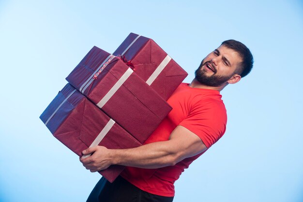 Человек в красной рубашке держит большой запас подарочных коробок