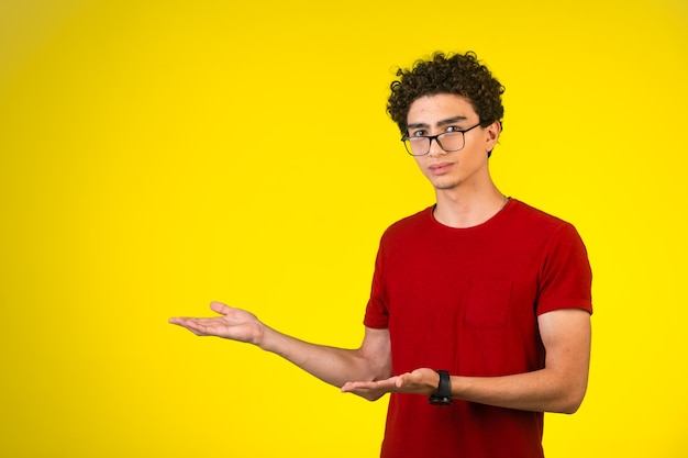 Man in red shirt introducing something with hand gests and looks satisfied