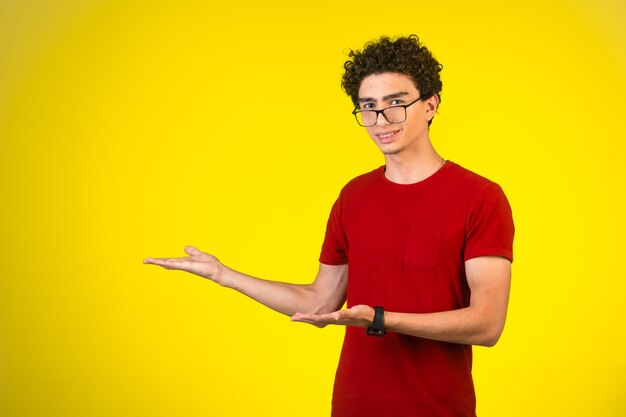 Man in red shirt introducing something with hand gests.