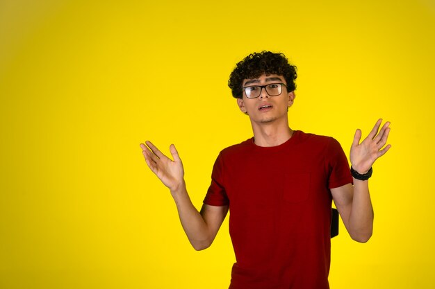 Man in red shirt opens his arms and makes surprized face