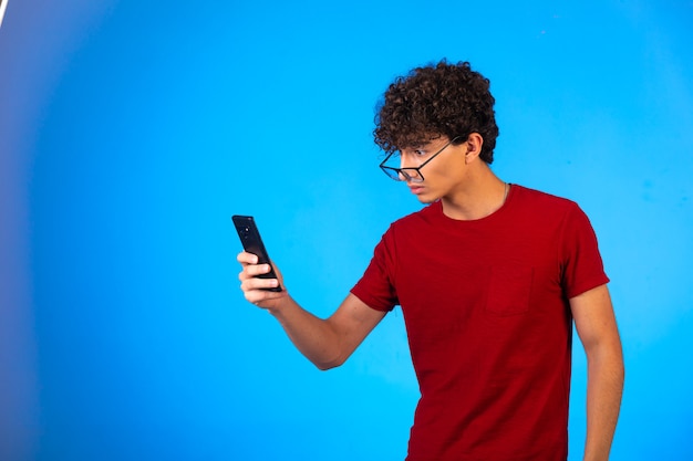 Man in red shirt taking selfie or making a phone call and looks upset