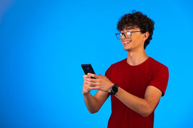 Man in red shirt taking selfie on a smartphone.