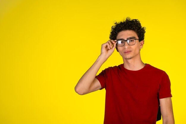 Man in red shirt touching his eyeglasses and flirting