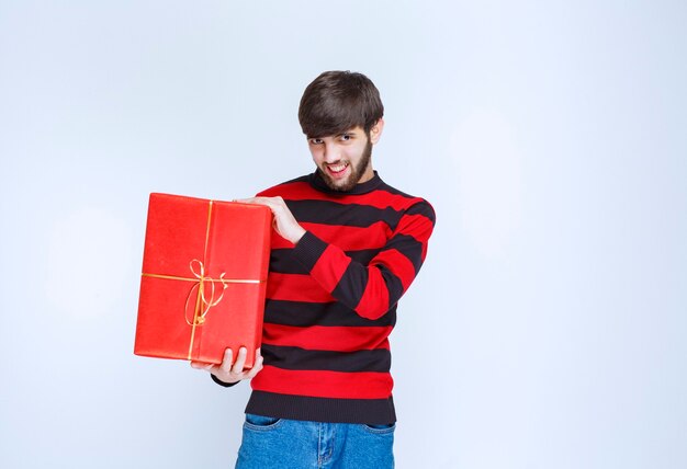 빨간색 선물 상자를 들고 빨간색 줄무늬 셔츠를 입은 남자, 배달 및 제시
