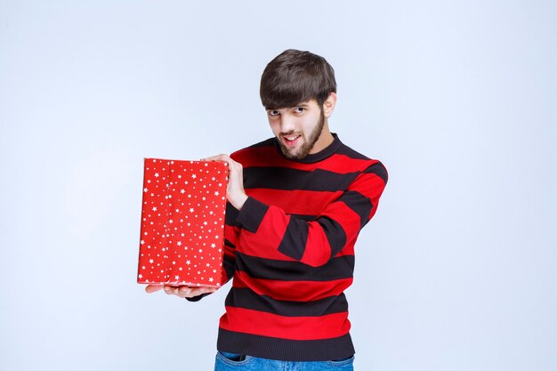 Man in red striped shirt holding a red gift box, delivering and presenting it