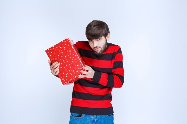 빨간색 선물 상자가 달린 빨간 줄무늬 셔츠를 입은 남자