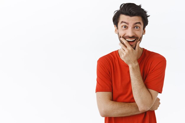 man in red t-shirt, laughing and touching bristle as getting curious, stare entertained and amused, smiling broadly