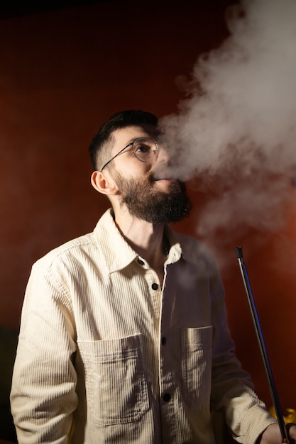 Man relaxing by vaping from a hookah in a bar