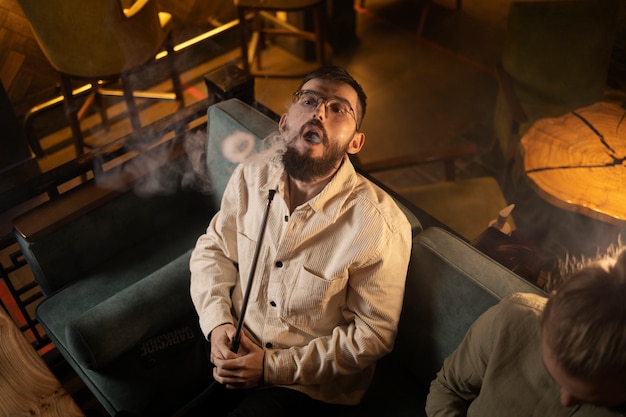 Man relaxing by vaping from a hookah in a bar