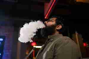 Free photo man relaxing by vaping from a hookah in a bar