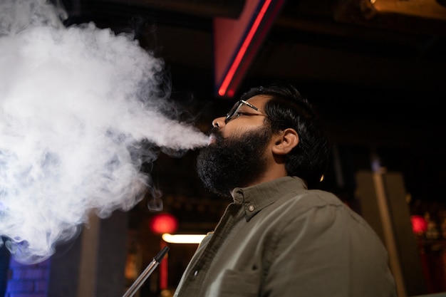 Man relaxing by vaping from a hookah in a bar