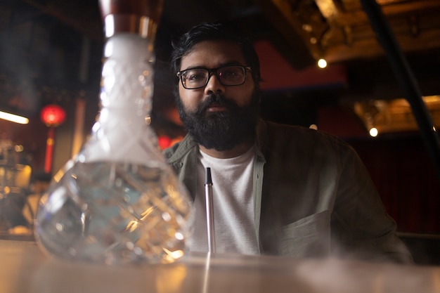 Man relaxing by vaping from a hookah in a bar