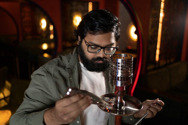 Foto gratuita uomo che si rilassa svapando da un narghilè in un bar