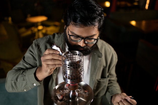 Man relaxing by vaping from a hookah in a bar