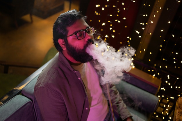 Man relaxing by vaping from a hookah in a bar