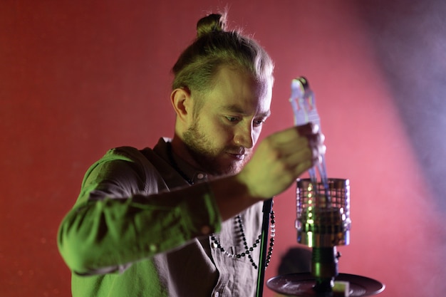 Free photo man relaxing by vaping from a hookah in a bar