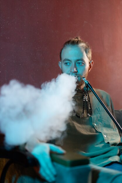 Man relaxing by vaping from a hookah in a bar