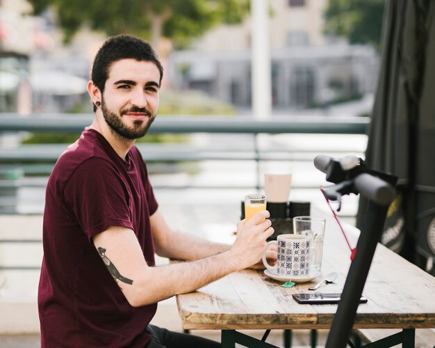 Man relaxing at cafe table with defocused e-scooter