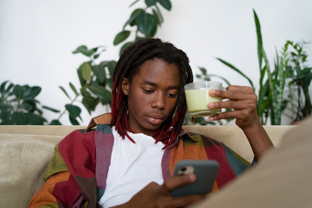 Free photo man relaxing at home and enjoying a cup of matcha tea