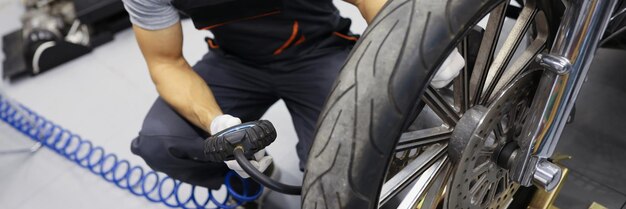 Man repairman inflating motorcycle tires in auto repair shop motorcycle service concept