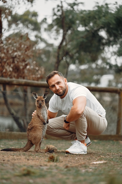 Man in the reserve is playing with a kangaroo