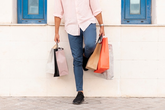 Man resting on the wall while holding shopping bags