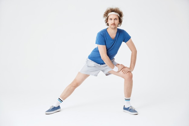 Man in retro sportswear warming up muscles before working out