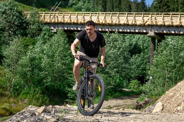 A man rides a bicycle in a mountainous area in the forest