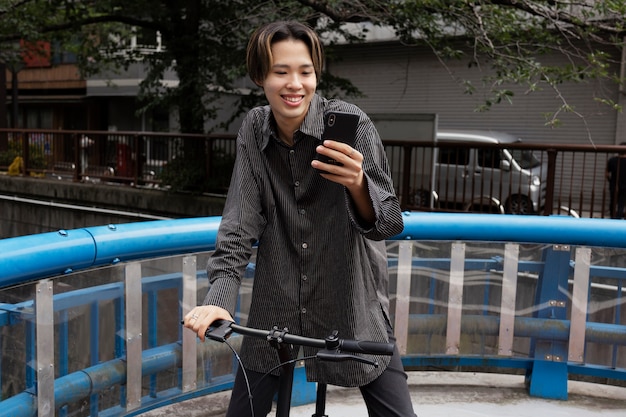 街で自転車に乗ってスマホで自撮りする男