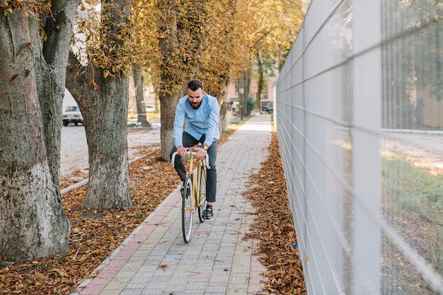 Free photo man riding bicycle near fence